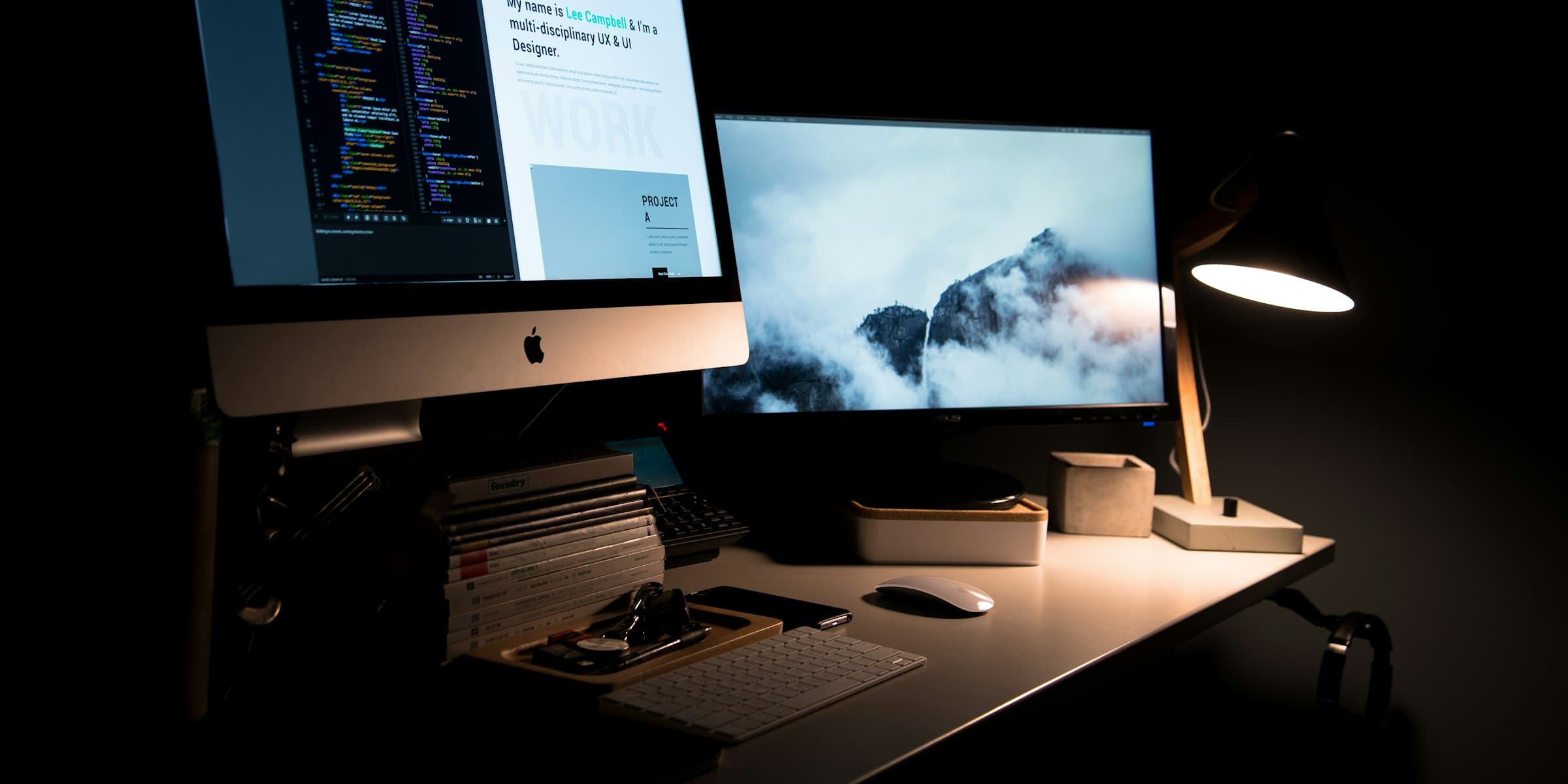 Modern creative workspace with desktop monitors and a desk lamp